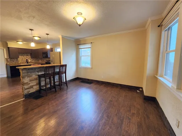 a view of a room with wooden floor and kitchen view