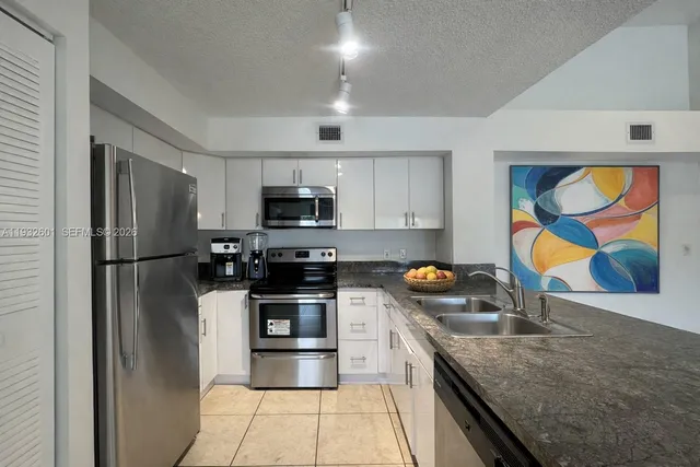 a kitchen with stainless steel appliances granite countertop a refrigerator and a stove top oven