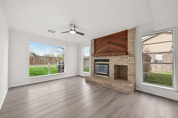 an empty room with windows fireplace and wooden floor