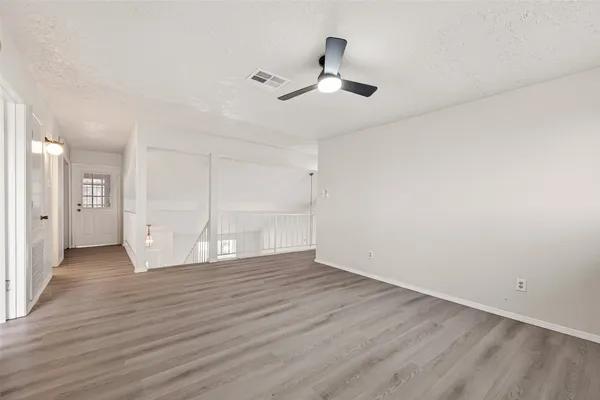 an empty room with wooden floor and windows