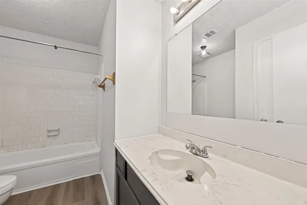 a white bath tub sitting next to a white toilet and vanity