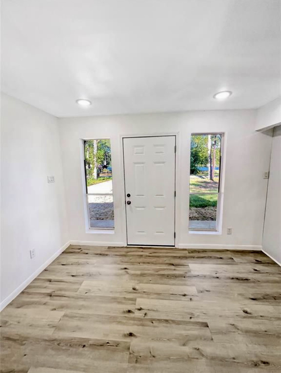 408 Commanche Road Conroe, TX 77316 - Photo 9 of 25 Bright and inviting entryway featuring sleek hardwood floors, recessed lighting, and abundant natural light from tall windows.