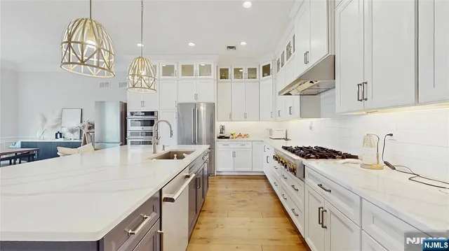 a kitchen with stainless steel appliances a stove a sink dishwasher and white cabinets with wooden floor