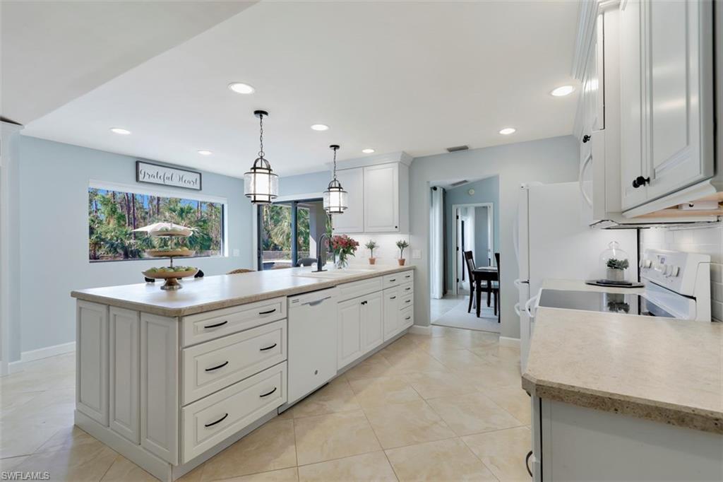 5260 Mahogany Ridge Drive Naples, FL 34119 - Photo 7 of 15 a kitchen with kitchen island granite countertop a sink and cabinets