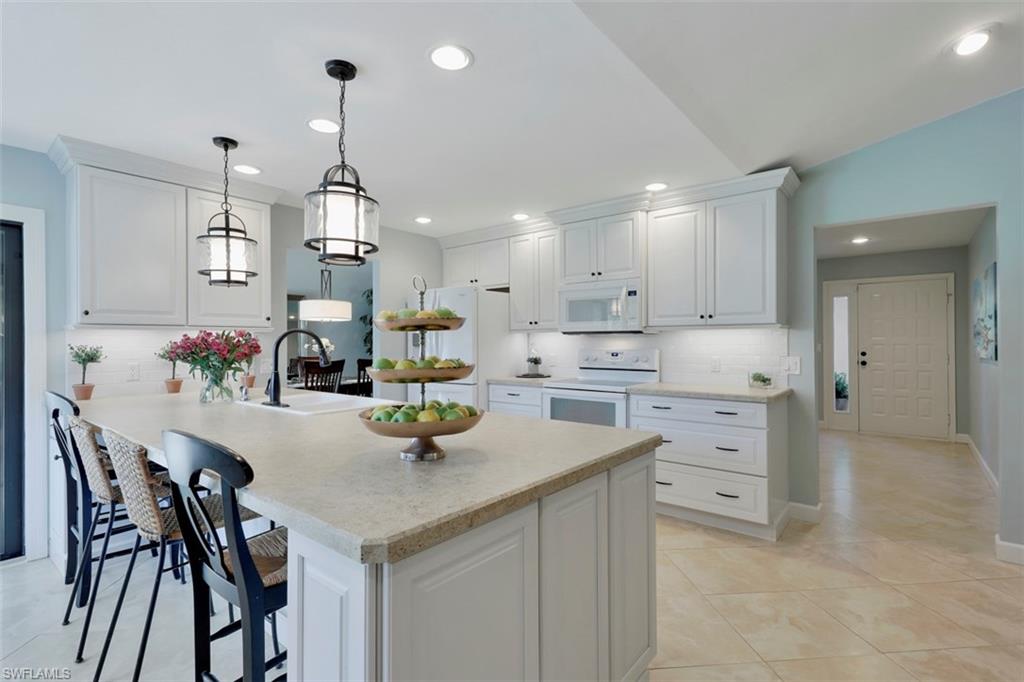 5260 Mahogany Ridge Drive Naples, FL 34119 - Photo 8 of 15 a kitchen with white cabinets and stainless steel appliances