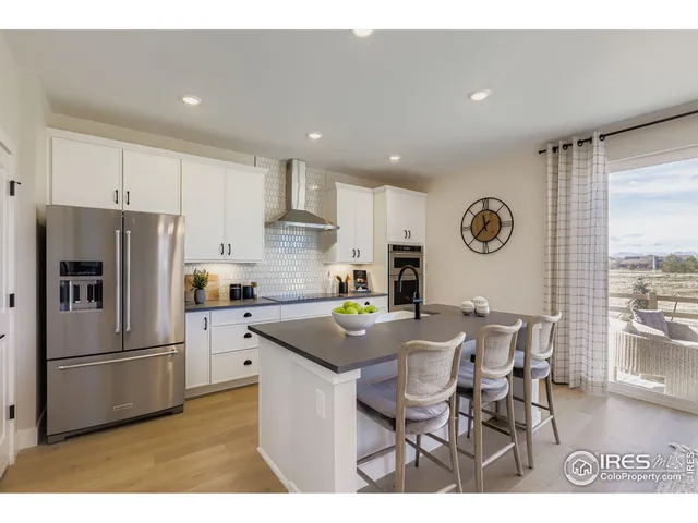 a kitchen with a refrigerator a stove a dining table and chairs