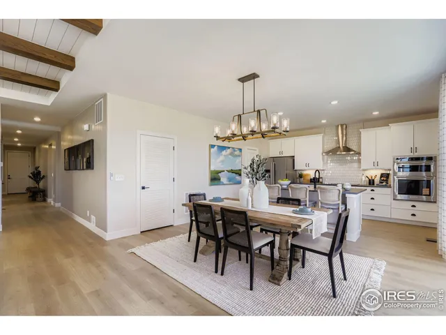 a view of a dining room and livingroom with furniture wooden floor a rug a painting and a chandelier