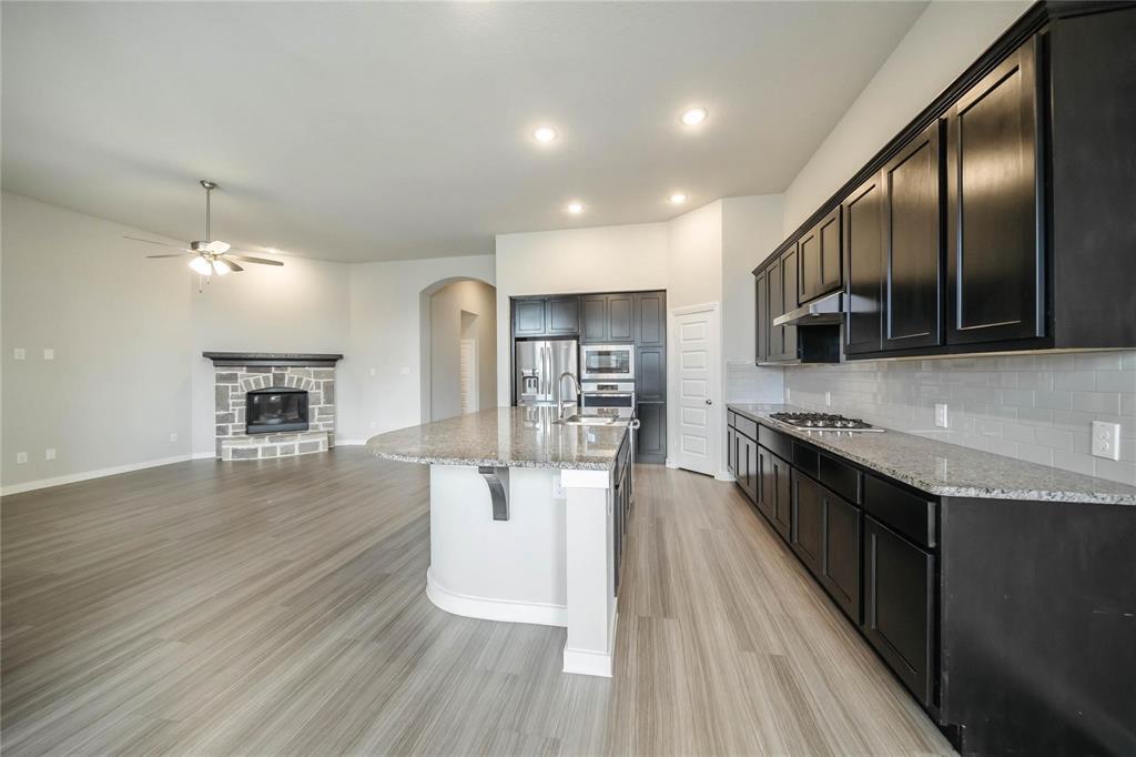 1113 Sheldon Drive Anna, TX 75409 - Photo 17 of 35 a large kitchen with stainless steel appliances granite countertop a lot of counter space and wooden floor