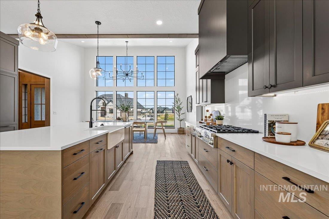 665 Watkins Street Middleton, ID 83644 - Photo 5 of 34 Kitchen featuring light wood finished floors, a chandelier, a towering ceiling, pendant lighting, and light stone countertops