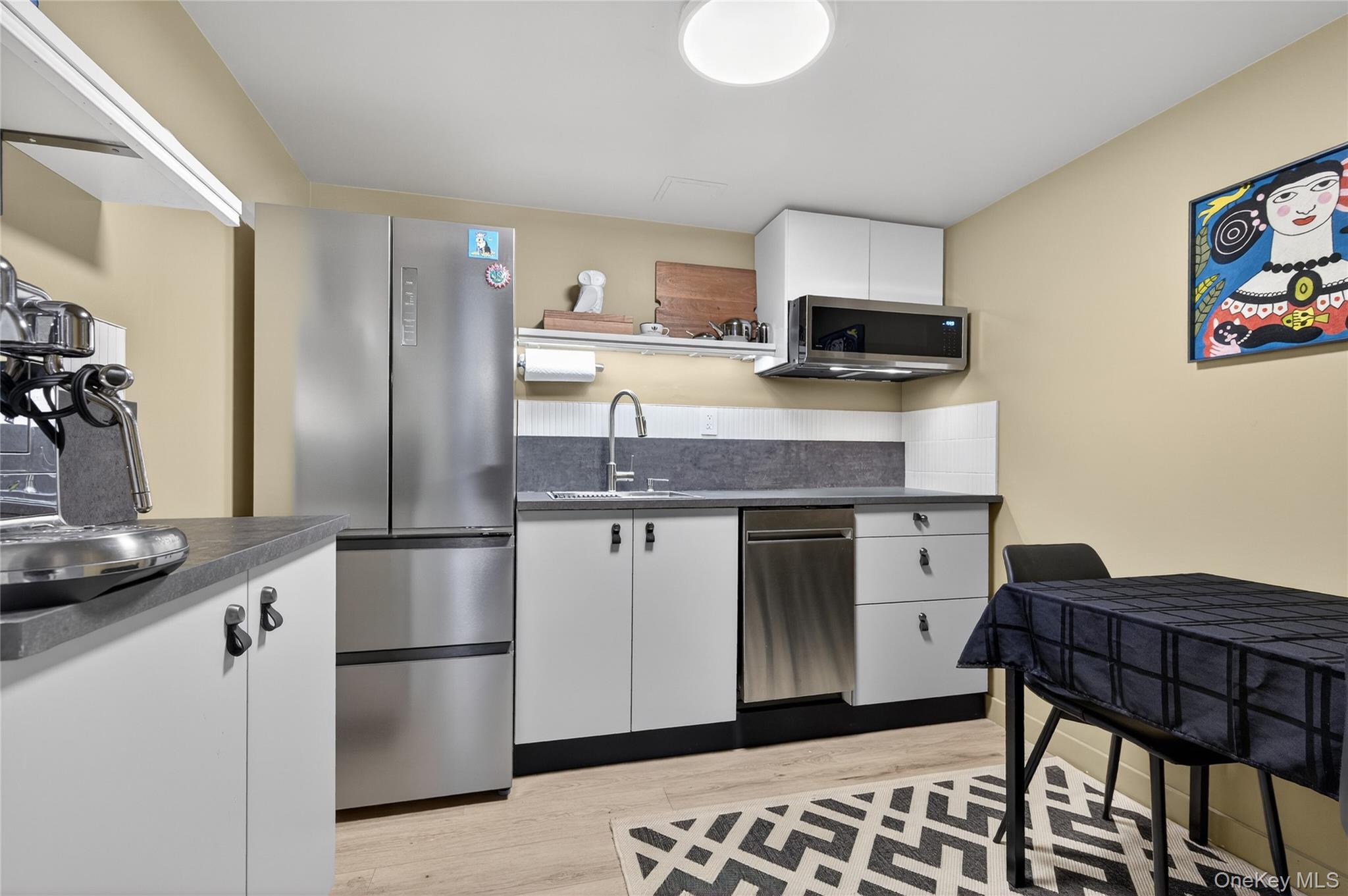 3 Beacon Hill Road Port Washington, NY 11050 - Photo 29 of 43 a kitchen with stainless steel appliances granite countertop a refrigerator a stove a sink a dining table and chairs
