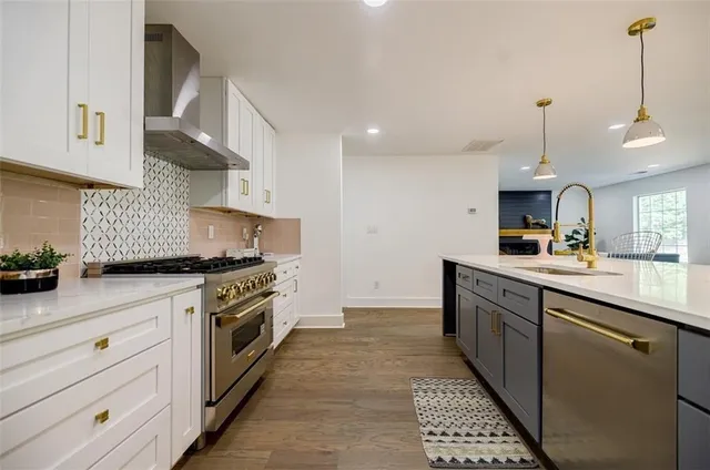 a kitchen with stainless steel appliances granite countertop a sink a stove and a wooden floors
