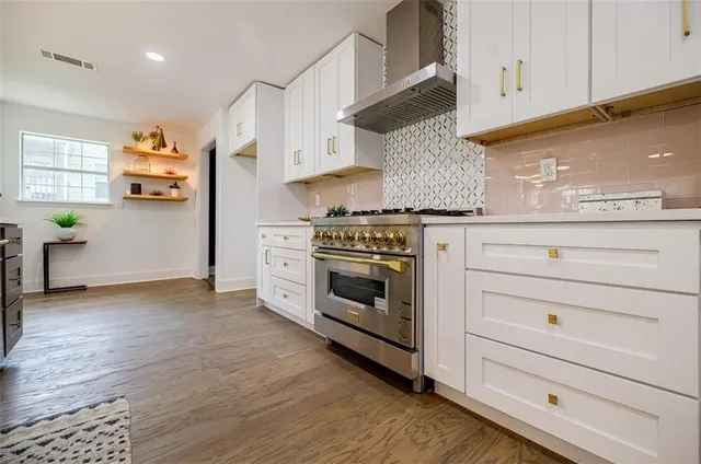 a kitchen with stainless steel appliances white cabinets and a wooden floor