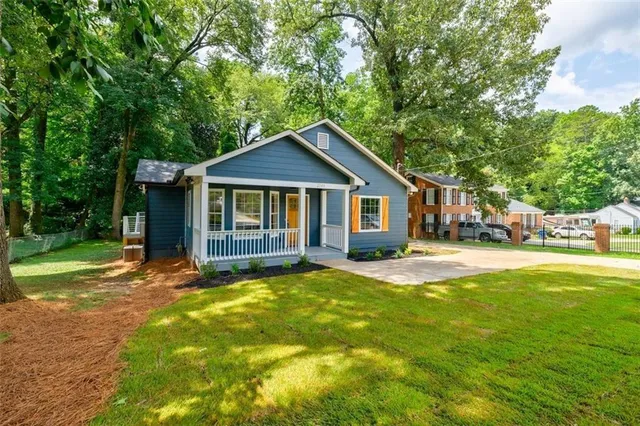 a view of a house with a yard and large tree