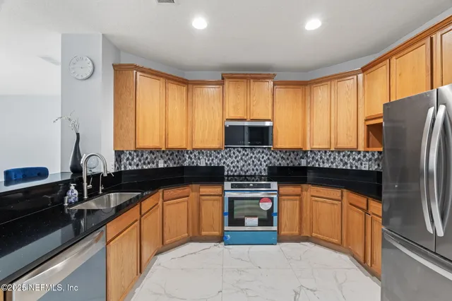a kitchen with stainless steel appliances granite countertop a stove a sink and a microwave