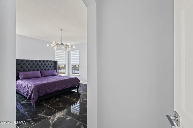 a bedroom with a large bed chandelier and a window