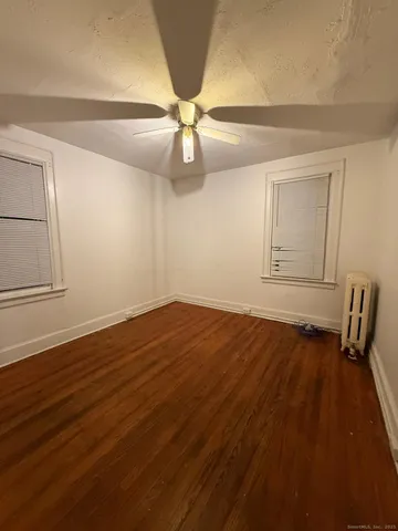 an empty room with wooden floor fan and windows