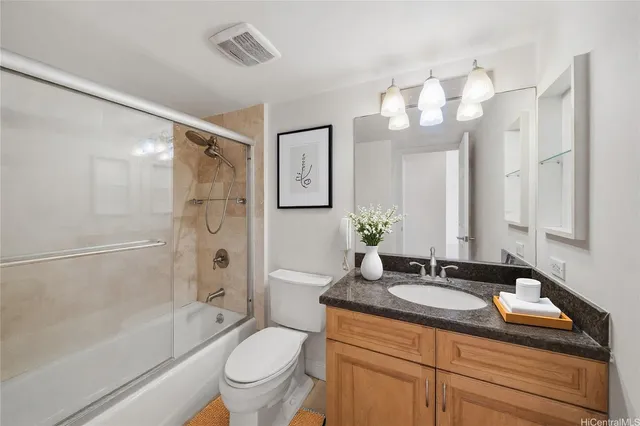 a bathroom with a granite countertop sink a toilet a mirror a bathtub and shower