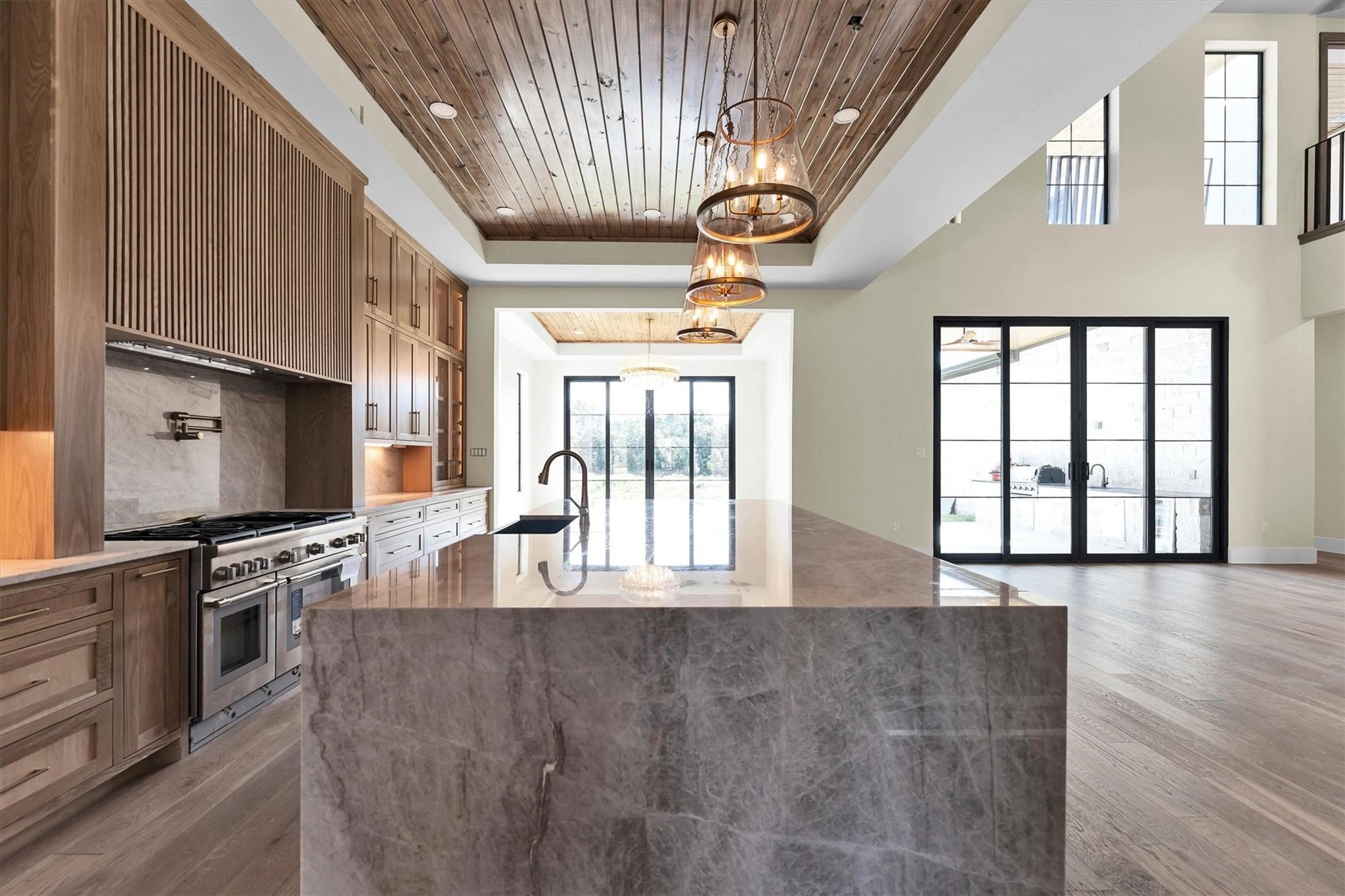 23701 Birch Grove Road Montgomery, TX 77316 - Photo 13 of 50 Experience culinary luxury in this stunning kitchen, featuring top-of-the-line Thermador appliances, exquisite wooden cabinetry, and elegant marble countertops, all under a beautifully crafted wood-paneled ceiling.
