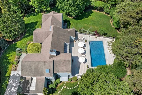 an aerial view of a house with outdoor space and trees all around