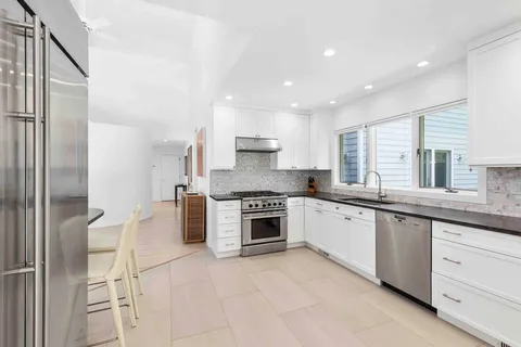 a large kitchen with stainless steel appliances granite countertop a stove a sink and a refrigerator