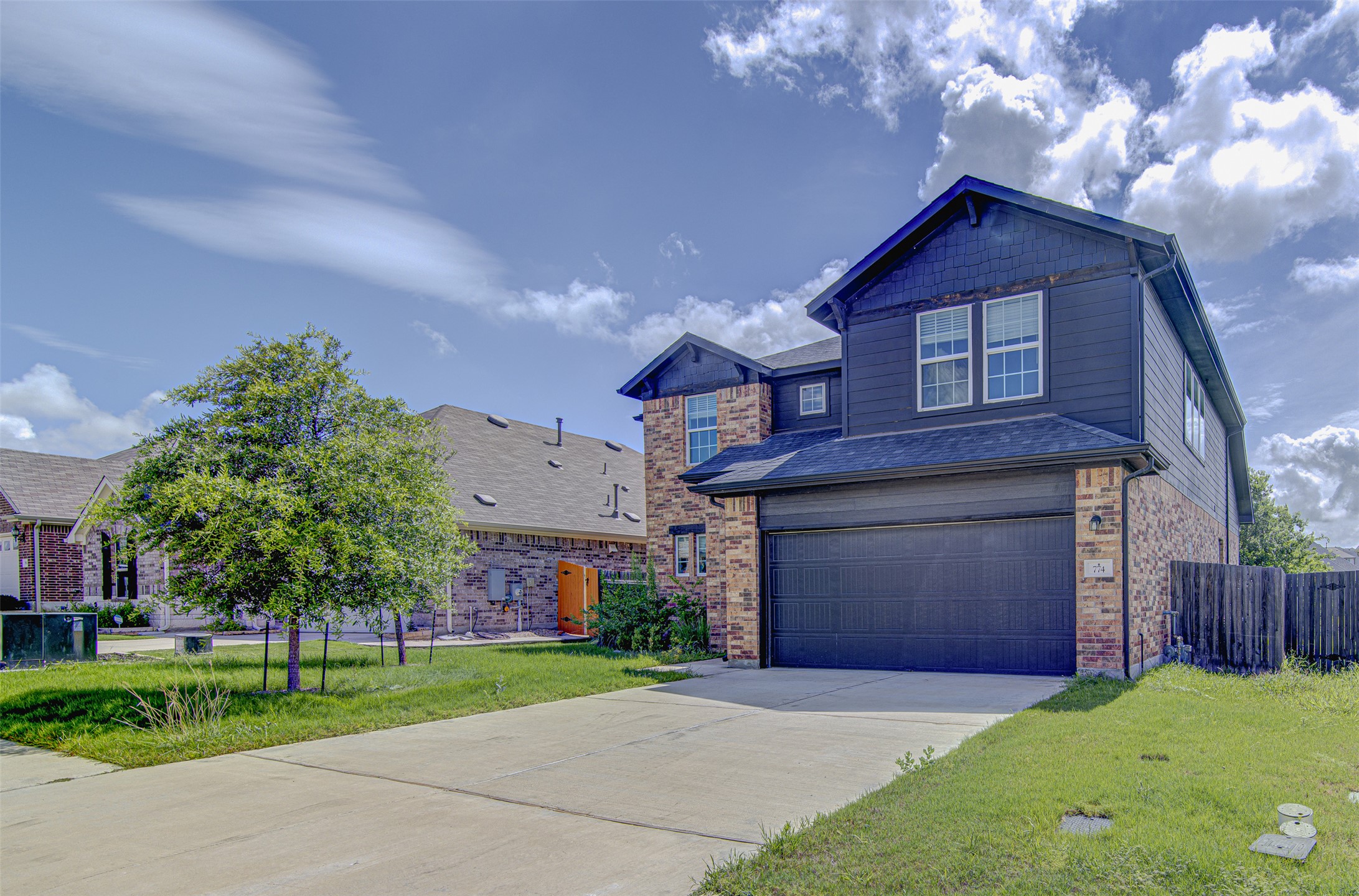 774 Cherrystone Loop Buda, TX 78610 - Photo 2 of 38 A well-maintained facade showcasing brick and siding, complemented by a neatly paved driveway and verdant lawn.