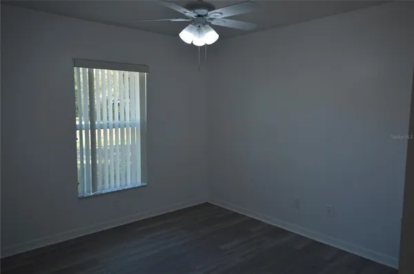 an empty room with a window and a fan