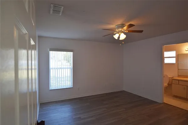 an empty room with wooden floor closet and windows
