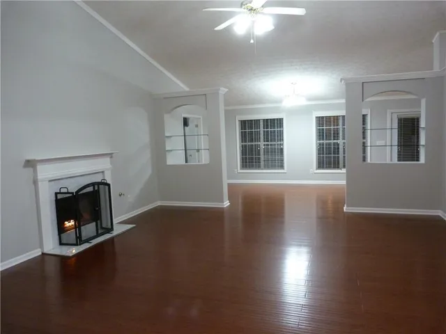 an empty room with wooden floor fireplace and windows