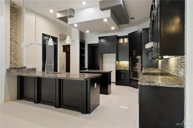 a large kitchen with granite countertop a large counter top cabinets and stainless steel appliances