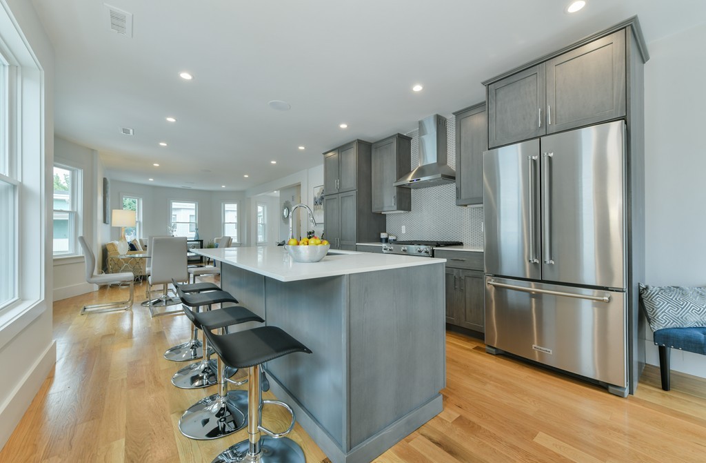 a kitchen with stainless steel appliances kitchen island granite countertop a refrigerator a sink dishwasher a stove and a dining table with wooden floor