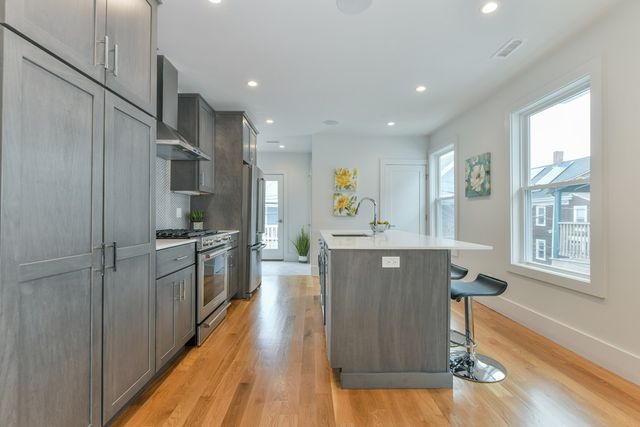 a kitchen with stainless steel appliances granite countertop a refrigerator a sink dishwasher a stove and white countertops with wooden floor