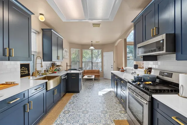 a kitchen with lots of counter top space a sink stainless steel appliances and cabinets