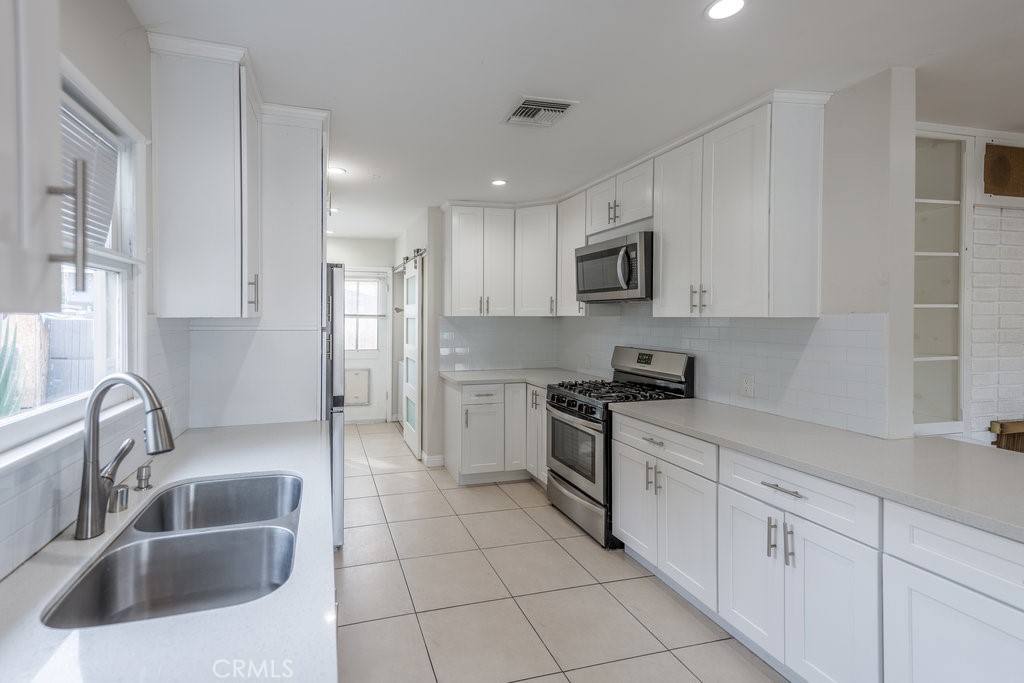 15744 Hart Street Van Nuys, CA 91406 - Photo 7 of 21 a kitchen with white cabinets a sink stove and refrigerator