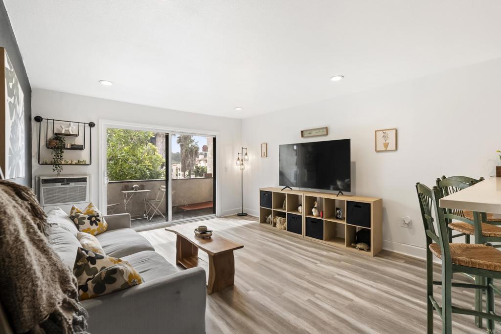 6780 Friars Road, Unit 243 San Diego, CA 92108 - Photo 13 of 31 a living room with furniture a flat screen tv and a floor to ceiling window
