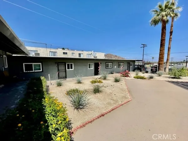 a front view of a house with garden and trees