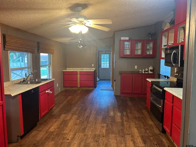 a large kitchen with stainless steel appliances granite countertop a stove a sink dishwasher a refrigerator and wooden floor