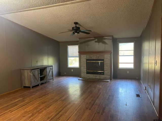an empty room with wooden floor fireplace and windows