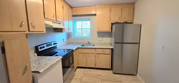 a kitchen with stainless steel appliances granite countertop a refrigerator a stove and a sink
