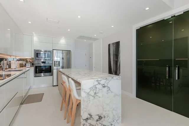 a kitchen with stainless steel appliances kitchen island granite countertop a refrigerator and a sink