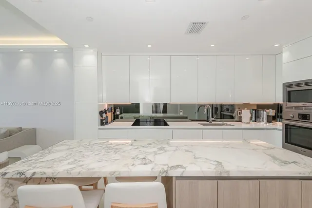 a view of a kitchen with kitchen island a sink stainless steel appliances and cabinets