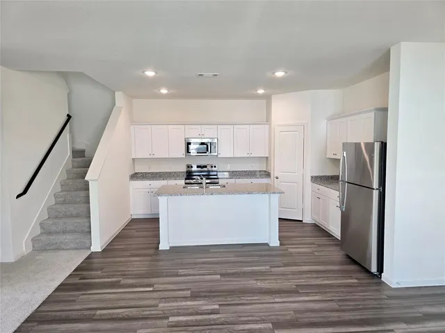 a view with kitchen island wooden floors stainless steel appliances and white cabinets
