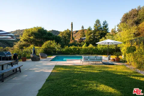 a view of a swimming pool with a table and chairs under an umbrella