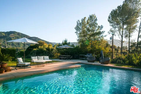 a swimming pool with plants and large trees