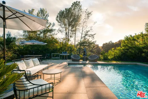 a view of swimming pool with lounge chair and dinning table under an umbrella