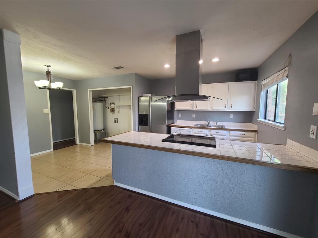5644 Perrin Street The Colony, TX 75056 - Photo 6 of 16 Kitchen with white cabinets, stainless steel fridge with ice dispenser, light wood-type flooring, island range hood, and kitchen peninsula