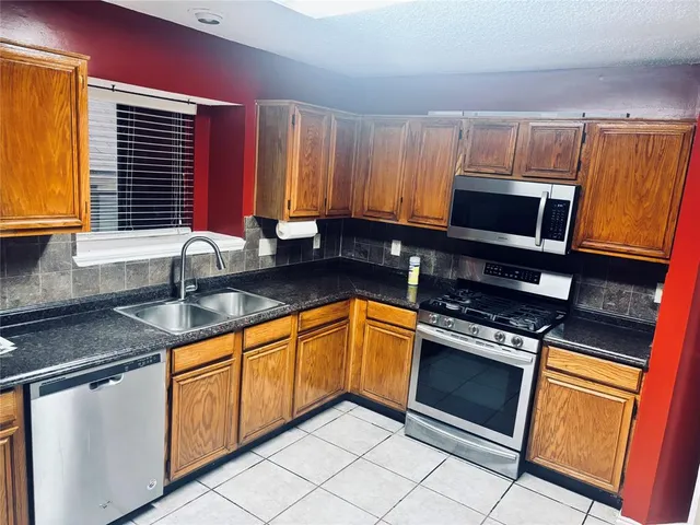 a kitchen with granite countertop a sink stainless steel appliances and cabinets