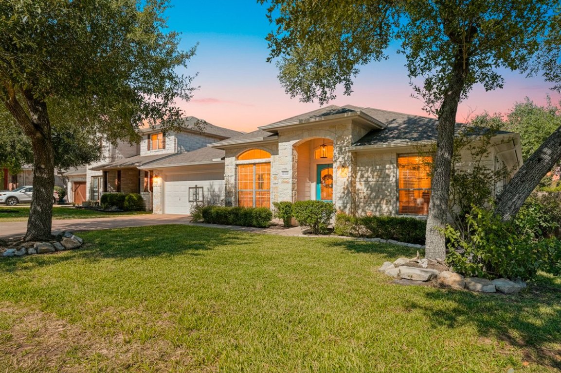 View of front of house with a front lawn, stone siding, concrete driveway, and an attached garage