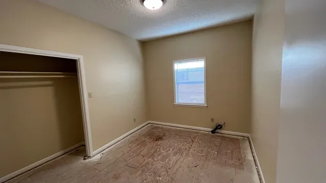 an empty room with a chandelier fan and windows