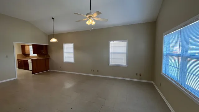 an empty room with windows and ceiling fan