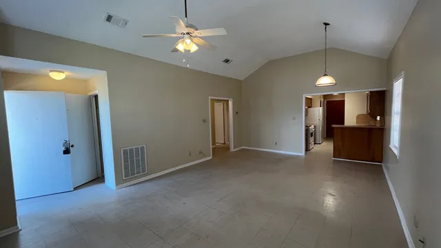 a view of empty room with a kitchen and chandelier fan